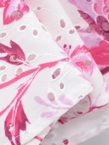 Close-up of white summer dress fabric with pink floral print and intricate embroidery