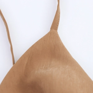 Close-up of thin straps and stitch detail on a camel brown cowl neck dress
