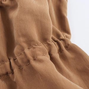 Macro view of brown smocked fabric detail showing elastic stitching and texture