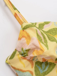 Gros plan des fines bretelles et de l'imprimé floral sur le tissu du haut jaune