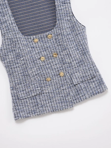 Close-up of blue tweed vest featuring gold embossed buttons and detailed woven texture