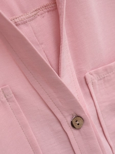 Detail of light pink summer shirt showing lapel collar and dark wood button texture
