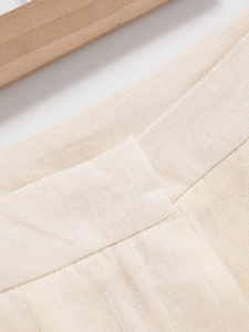Detailed macro view of the pleated high-waisted beige linen shorts for women with clean stitching