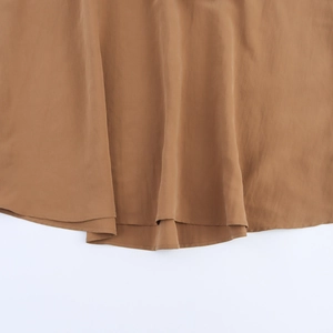 Macro view of brown backless dress hem with fine stitching and smooth draped fabric