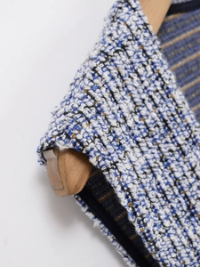 Detail of tweed fabric with blue and white weave and shimmering metallic gold threads