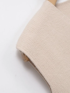 Détail du gilet en tricot col en V montrant les mailles fines sur cintre en bois