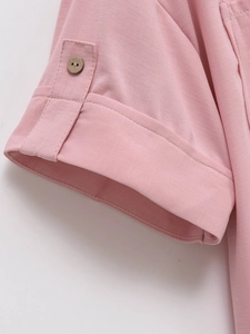 Detail of short sleeve cuff with decorative brown button on pink French style blouse