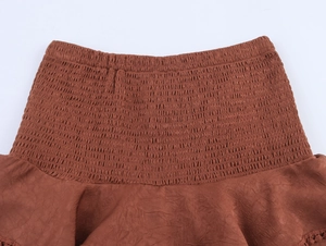 Detail of smocked elastic high waist and ruffled edge on a brown Y2K mini skirt