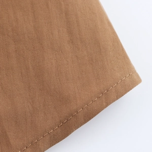 Detailed close-up of high-quality brown twill fabric with precision single-needle stitching