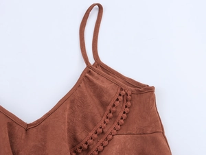 Detail of brown pleated camisole featuring delicate pom-pom trim on the V-neckline