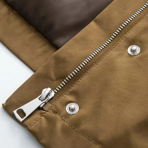 Detail of silver zipper and metal button on khaki utility jacket with premium stitching