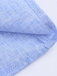 Gros plan sur la texture en lin de coton bleu clair et coutures soignées de la robe