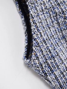 Macro view of blue tweed fabric texture with gold threads and black hem detailing