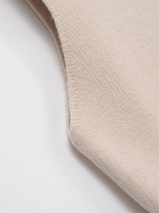 Gros plan détaillé sur les coutures invisibles et la texture tricotée de la veste beige