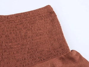 Detail showing the elastic smocked waistband and pleated texture of the brown Y2K skirt