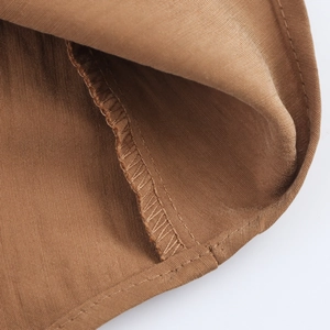 Close-up of brown dress hem showing neat double stitching and high-quality overlock edges