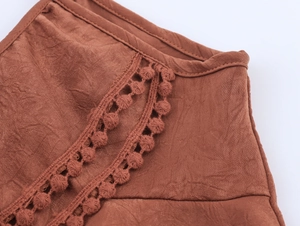 Detailed macro view of caramel-colored textured fabric with pom-pom lace edge trim