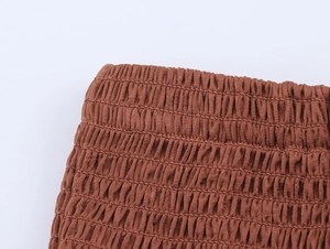 Close-up of brown smocking fabric texture with elastic pleated details on a summer skirt