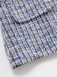 Macro shot of blue and white tweed fabric with gold metallic thread detail