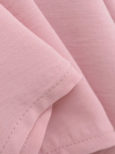 Close-up of precise stitching and premium light pink woven fabric on French style shirt