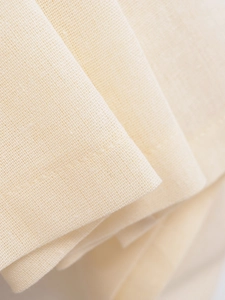 Macro shot of beige cotton-linen fabric showing clear weave texture and fine stitching