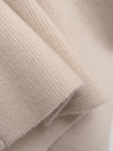 Texture macro du gilet en maille avoine montrant le cachemire doux et les détails côtelés