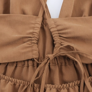Detail of the brown backless dress featuring tie-up straps and elastic pleated fabric