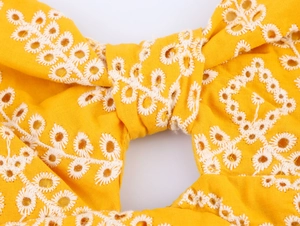 Macro di tessuto di cotone giallo con ricamo inglese bianco e motivi floreali fini