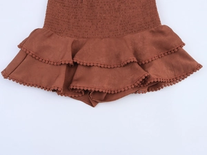 Detailed macro view of brown smocked waist skirt with double-layered pom-pom hem ruffles