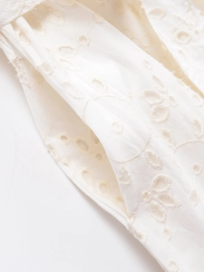 Macro shot of delicate white eyelet embroidery and stitching details on a summer shirt dress