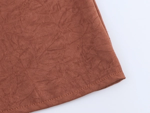 Close-up of brown halter top with pleated suede texture and premium stitched hem detail