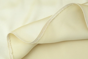 Detailed macro view showing high-quality overlock stitching on beige satin dress fabric