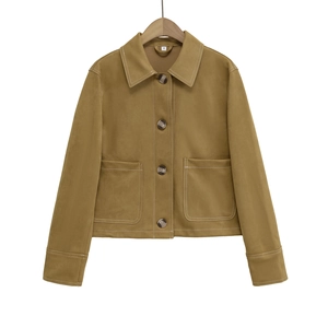 Détail des coutures contrastées et des grandes poches sur la veste en daim terreux