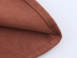 Close-up of tan linen fabric texture and double-stitch sewing detail on the top garment