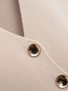 Gros plan du gilet en maille beige avec col en V et bouton en métal doré