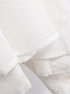 Macro detail of white embroidery hollow dress showing fine texture and hemming stitches