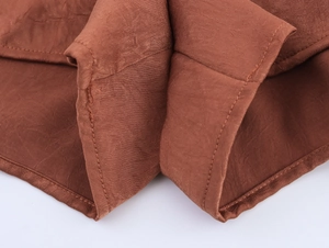 Close-up of rust brown fabric with detailed layered ruffles and neat stitching craft