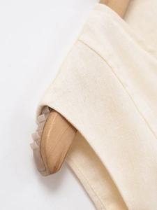 Close-up of beige cotton vest shoulder seam detailing with precise stitching texture