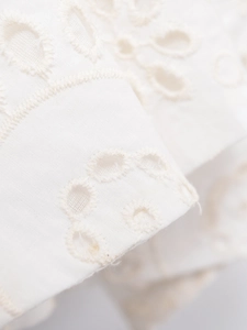 Detailed close-up of intricate white Broderie Anglaise embroidery on summer dress fabric