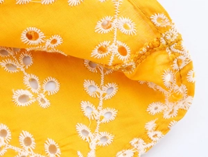 Vista macro del tessuto giallo con ricamo inglese a margherita e cuciture rifinite
