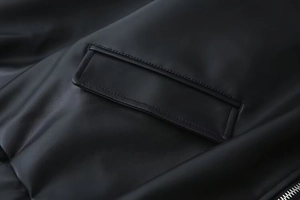 Close-up detail of black PU leather jacket showing pocket flap and silver metal zipper