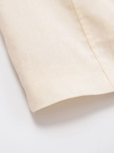 Close-up of off-white linen fabric showing dense woven texture and premium sewing craft
