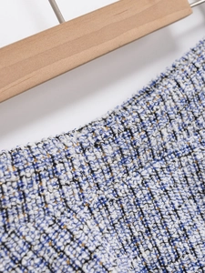 Close-up of blue and white tweed fabric with golden metallic threads and woven texture