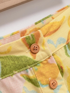 Détail de jupe taille haute avec boutons en bois et imprimés végétaux sur tissu jaune