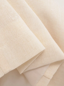 Close-up of the beige textured linen fabric with detailed stitching and soft draping