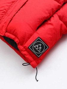Détail de doudoune rouge avec écusson montagne et cordon de serrage élastique réglable