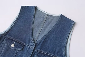 Détail de la combinaison en jean bleu foncé avec col en V et surpiqûres contrastantes