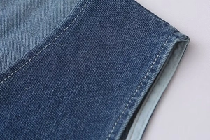 Détail des doubles coutures et de la texture du tissu sur la combinaison en jean bleu