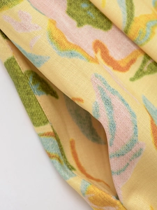 Gros plan sur un tissu jaune à motif floral montrant la texture et les détails abstraits