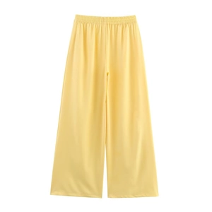 Detailed view of elastic high waist and flowy pale yellow wide-leg trousers